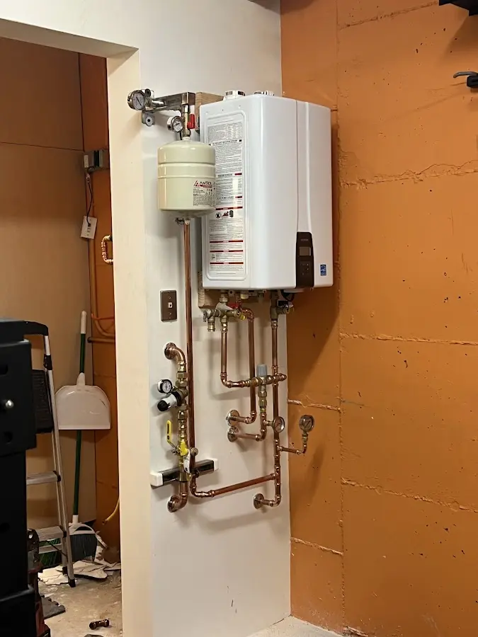 Plumbing technician inspecting water heater connections in Lennox
